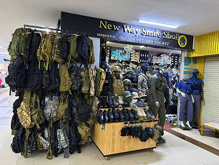 Tactical gear display at New Way Smile Shop with backpacks, helmets, and outdoor accessories.