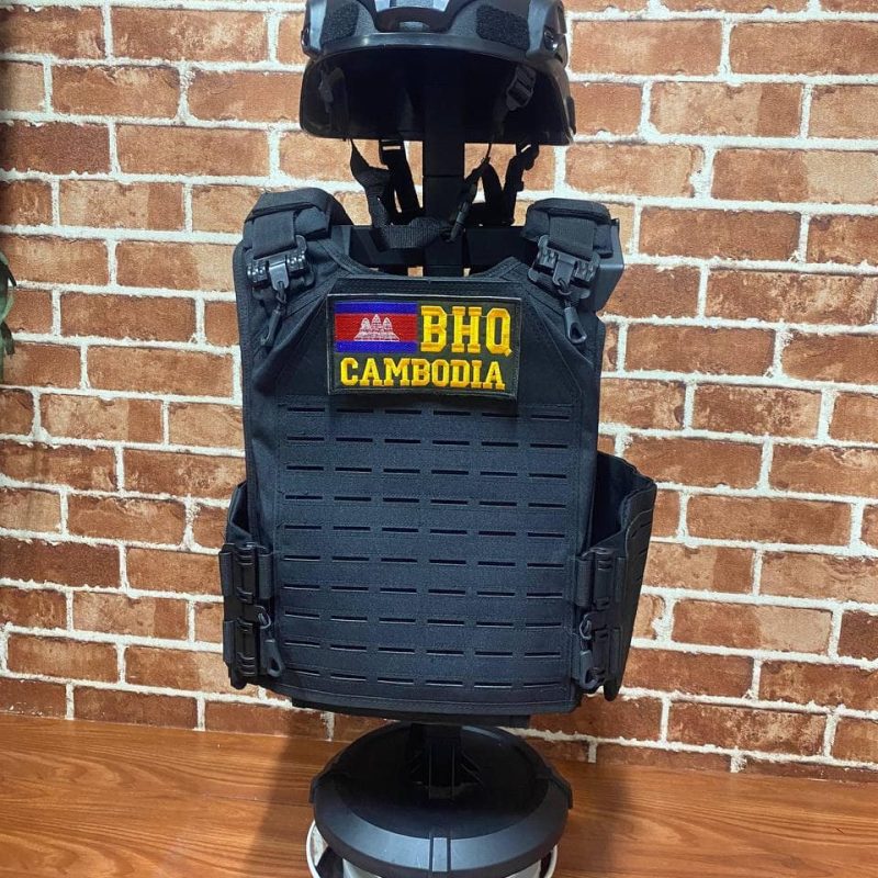 Black tactical vest with Cambodia patch and helmet on display.