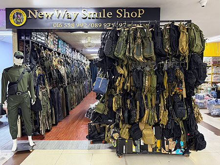 Tactical gear display with camouflage bags and clothing at New Way Smile Shop in Phnom Penh.