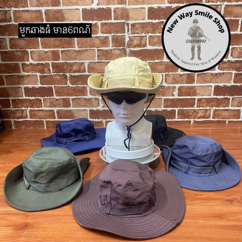 Outdoor wide-brim hats in beige, green, purple, blue, and black displayed on a wooden desk.