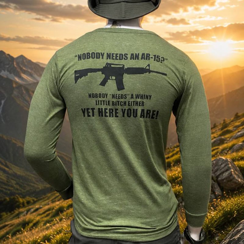 Green tactical shirt with AR-15 graphic and humorous quote, outdoor mountain background at sunset.