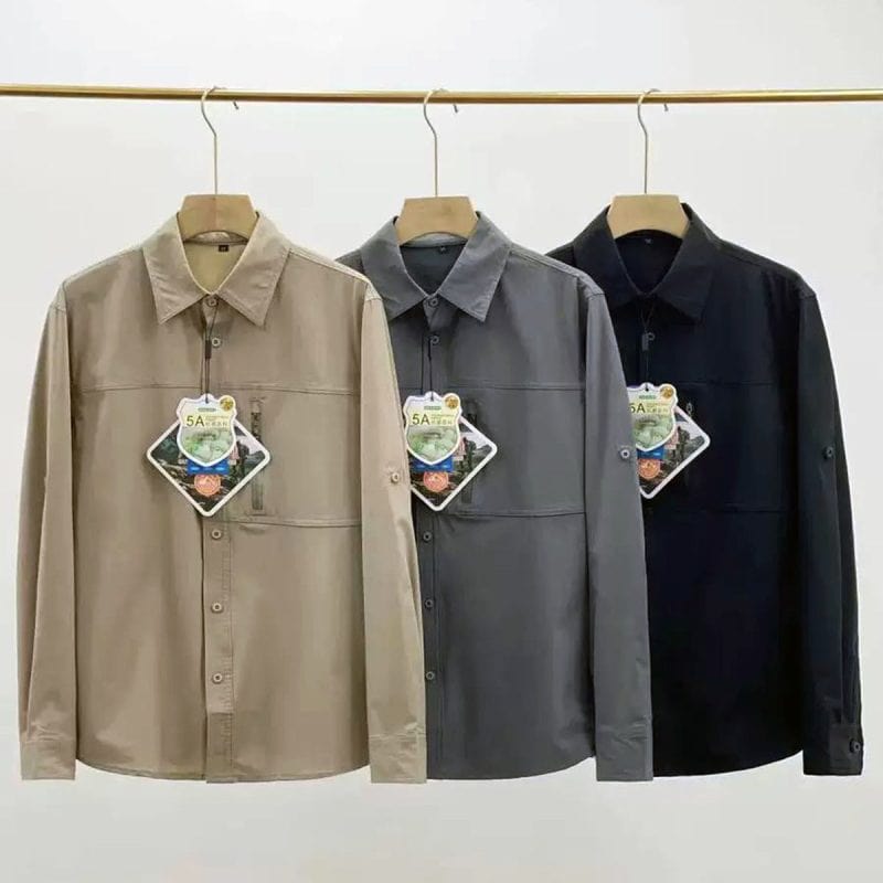 Three long-sleeved outdoor shirts in beige gray and black displayed on hangers.