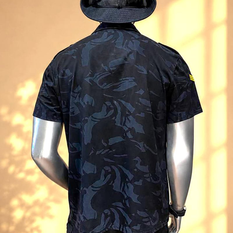 Dark camouflage tactical shirt with chest pockets, short sleeves, and a hat, designed for outdoor and tactical use.